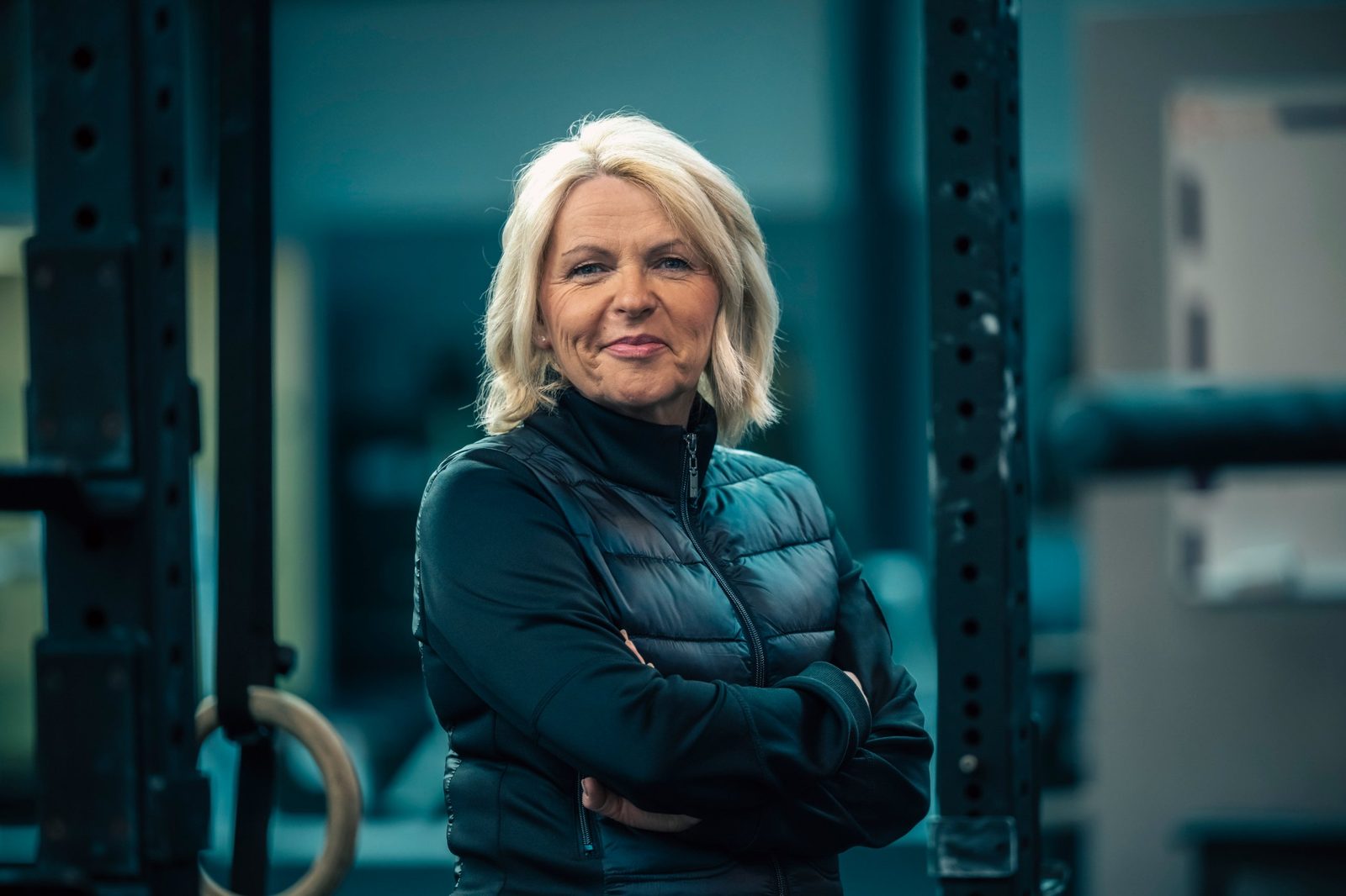 Anja Lorenz im Trainingsraum, mit verschränkten Armen in die Kamera lächelnd